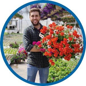 Trainee in a greenhouse holding a hanging flower basket